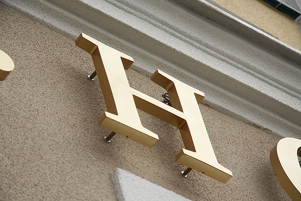 Złote litery przestrzenne podświetlane do tyłu na elewacji hotelu Akira w Wrocławiu