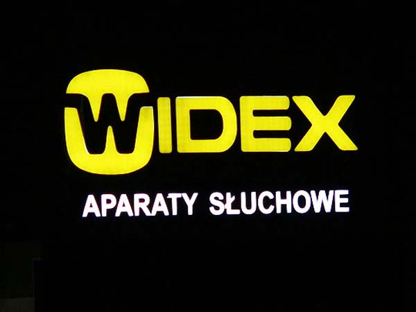 Logo firmy Widex na dachu budynku widok z autostrady A4 w nocy