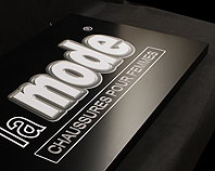 Szyld reklamowy dla salonu sprzdaży butów wykonany czarnym lakierowanym na matowo aluminium