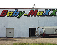 Szyld reklamowy z blachy aluminiowej na ścianie hali sprzedazy Baby-Maxx